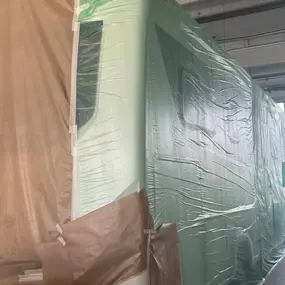 Lkw in einer Werkstatt, vollständig mit Folie und Papier zur Lackierung abgedeckt.